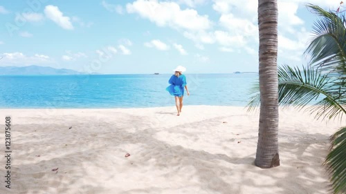 Young beautiful women in the blue tunic on the sunny tropical beach photo