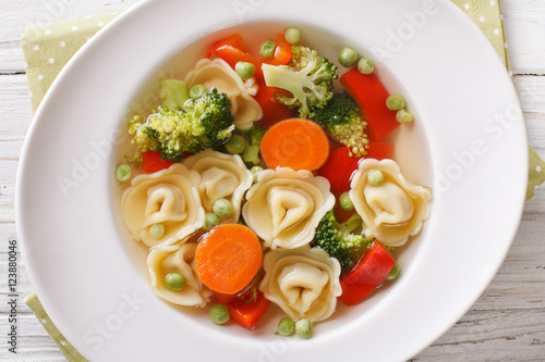Italian tortellini soup with broccoli, peas, carrot and pepper close-up. horizontal top view