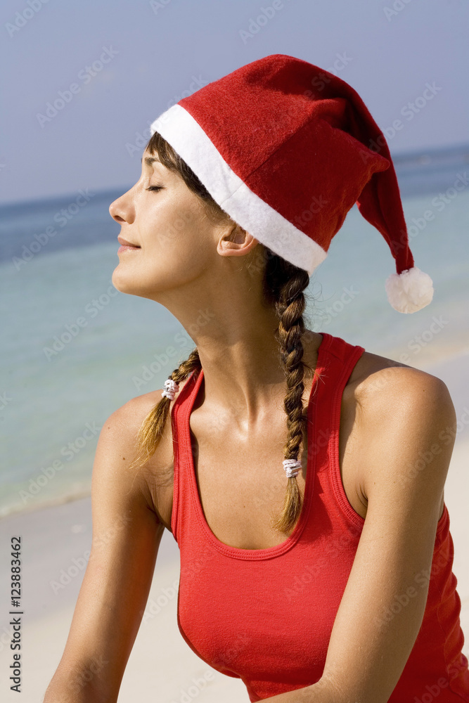 Obraz premium portrait d'une femme qui bronze sur la plage avec un bonnet de père Noël
