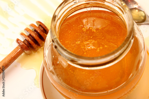 Delicious sweet honey with dipper in glass jar.