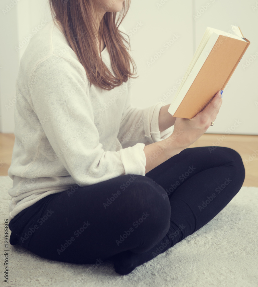 young woman sitting on floor and reading a book