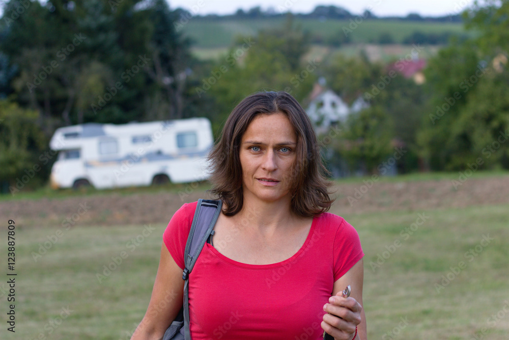Woman goes from a parked camper, caravan parked in the distance. woman in a red shirt on a trip. Woman goes from a parked camper, caravan parked in the distance. woman in a red shirt on a trip.