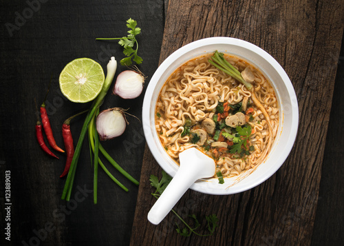 Instant noodles in plastic bowl and vegetable side dishes on woo photo