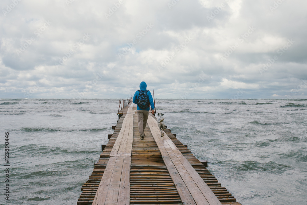 man walking on wooden pier on the background of stormy sea