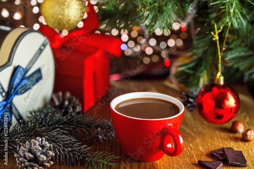 Traditional winter hot chocolate drink near gift boxes under Christmas tree. Delicious cocoa beverage on a table.