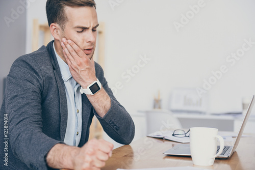 Fotografi Handsome busy man having toothache on the work place.