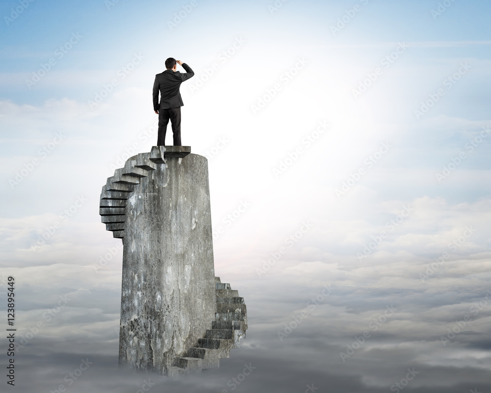 Businessman gazing on top of spiral tower Businessman gazing on top of spiral tower