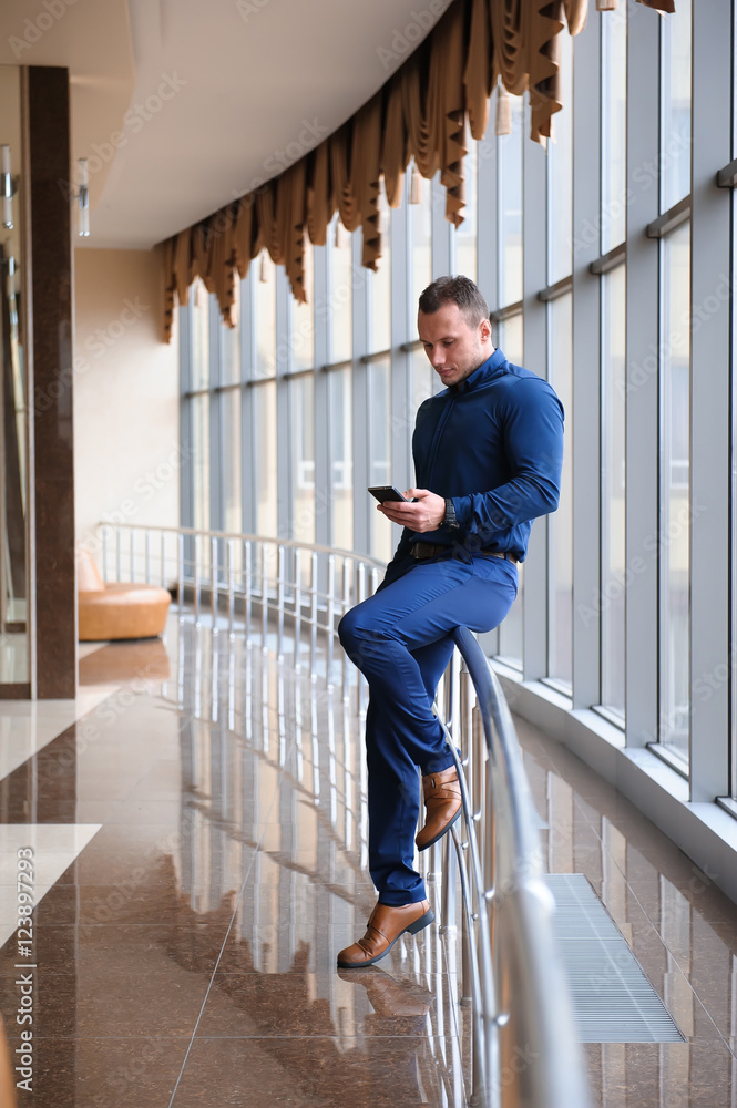 businessman looking through the phone by the window businessman looking through the phone by the window