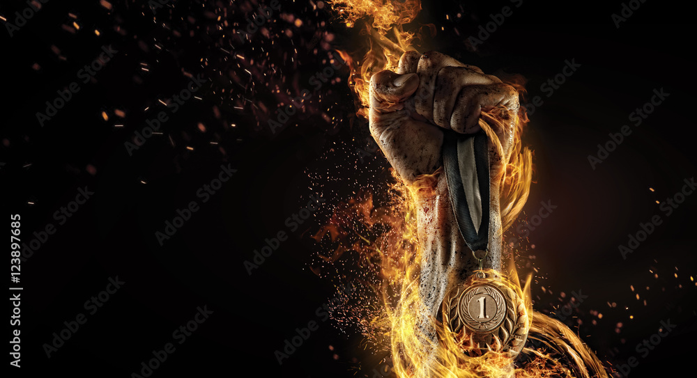 Sport. Man's hand holding up trophy medal. Winner in a competition. Fire and energy

