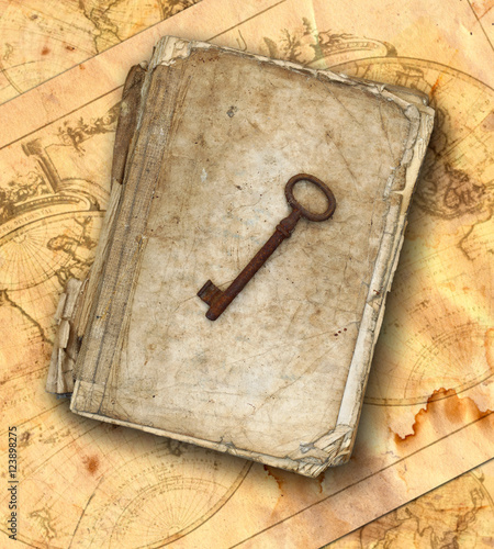 Worn and tattered book and old rusty key on the old maps