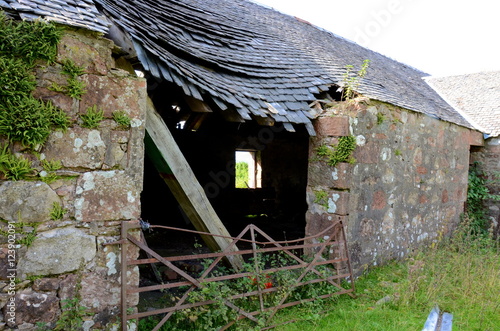 A dilapidated farmhouse which has fallen into ruins photo