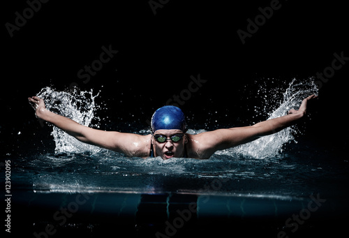 Profesional woman swimmer swim using breaststroke technique on the dark background