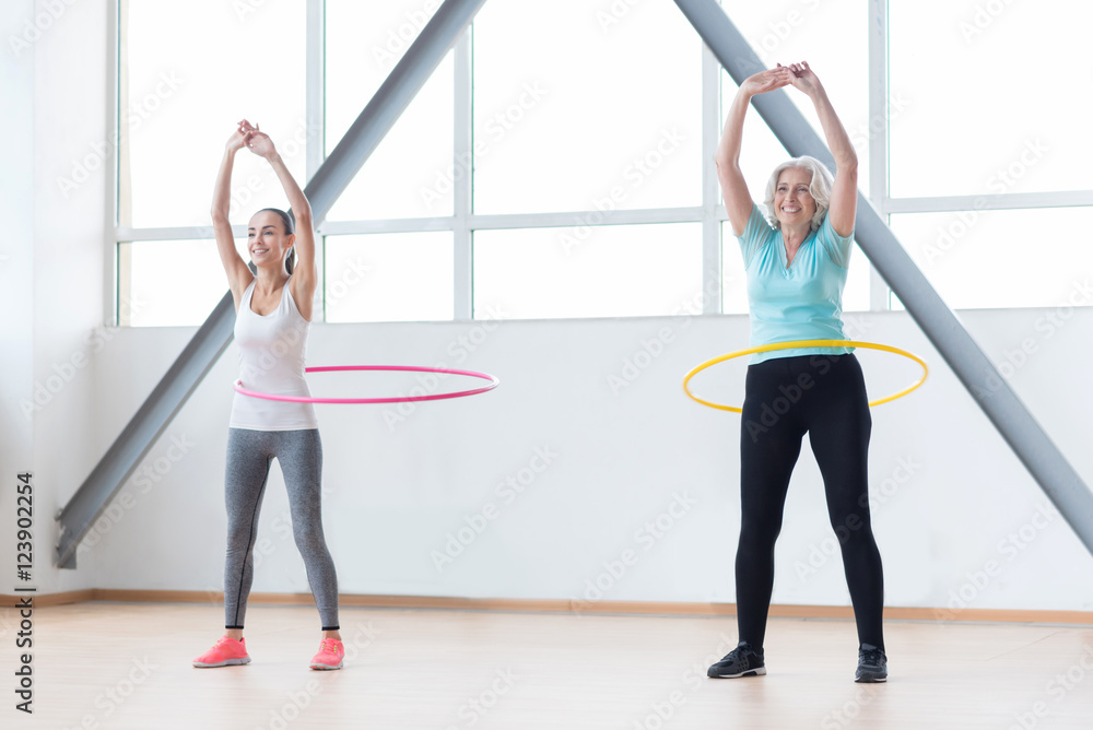 Obraz premium Persistent positive women exercising with hula hoops