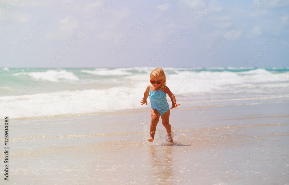 little girl run play with waves on the beach