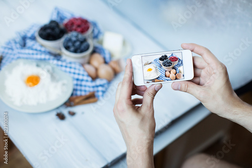 Hand with smartphone taking food photo.