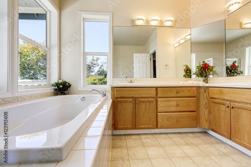 Luxury bathroom interior with wooden cabinets and white bathtub