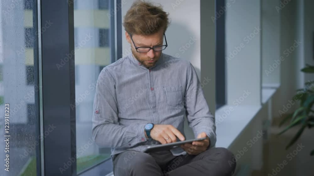 Young businessman is sitting at window and browsing Young businessman is sitting at window and browsing