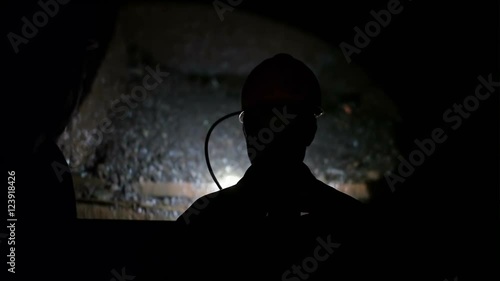 Miner go down into a mine shaft in the elevator cage, silhouette in darkness