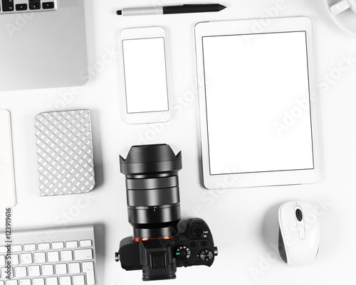 Top view of photographer workplace: Keyboard, tablet, camera and smartphone on white desk background