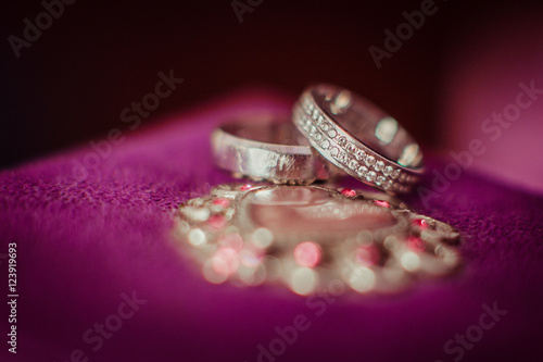 Silver wedding rings lie over the violet pillow © pyrozenko13
