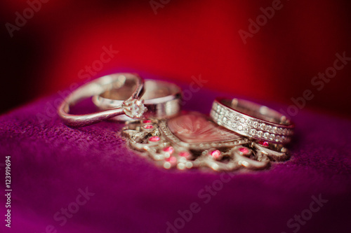 Wedding rings made of white gold lie over the violet pillow
