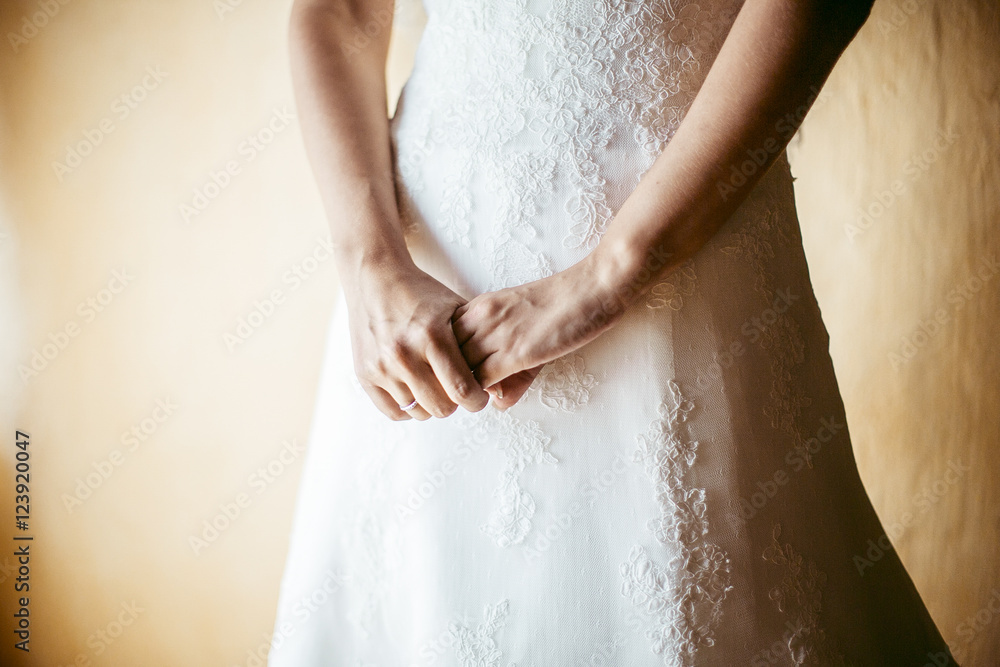 A closeup of bride's hand holding each other on the skirt