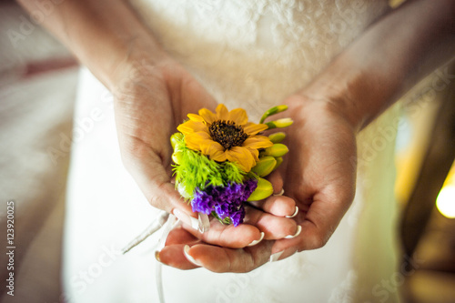 Bride holds in her hands yellow and biolet boutonniere photo