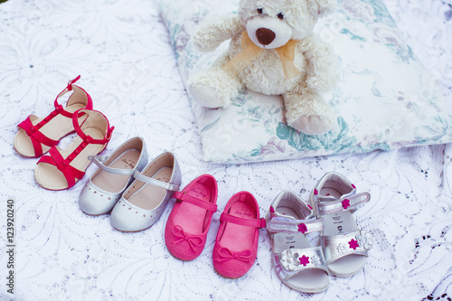 Little girl's shoes stand on the white bed