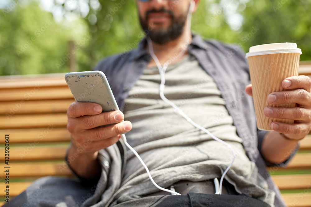 Fototapeta premium man with earphones and smartphone drinking coffee