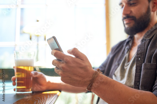 close up of man with smartphone and beer at pub