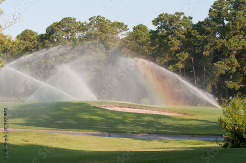 A rainbow formed while watering a beautiful golf course