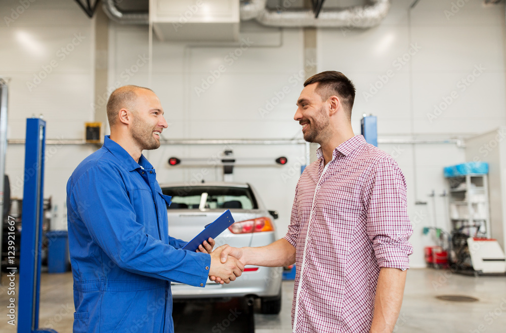 auto mechanic and man shaking hands at car shop auto mechanic and man shaking hands at car shop