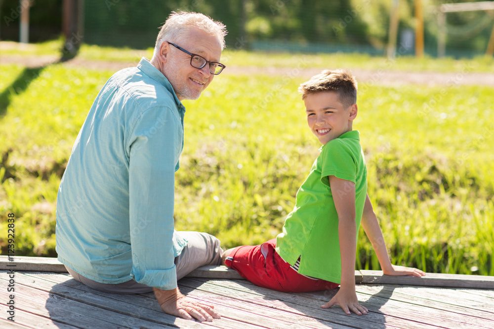 Fototapeta premium grandfather and grandson sitting on river berth