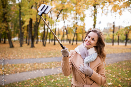 woman taking selfie by smartphone in autumn park