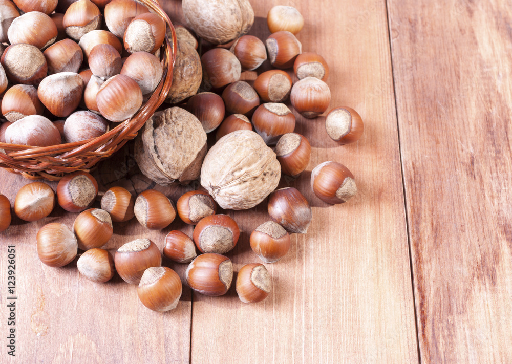 Walnuts and hazelnuts in a basket on wooden background Walnuts and hazelnuts in a basket on wooden background