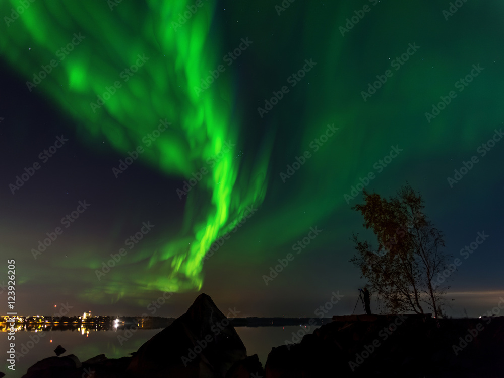 Northern lights over sea and a city in the background