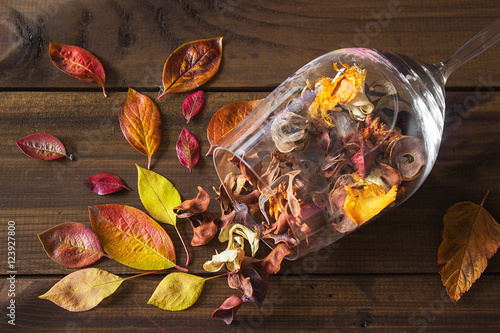 Autumn leaves in a wine glass on wooden table background