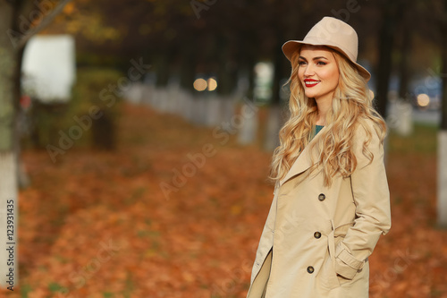 Beautiful elegant woman standing in fashionable beige hat in a park in autumn. free space. © lenblr