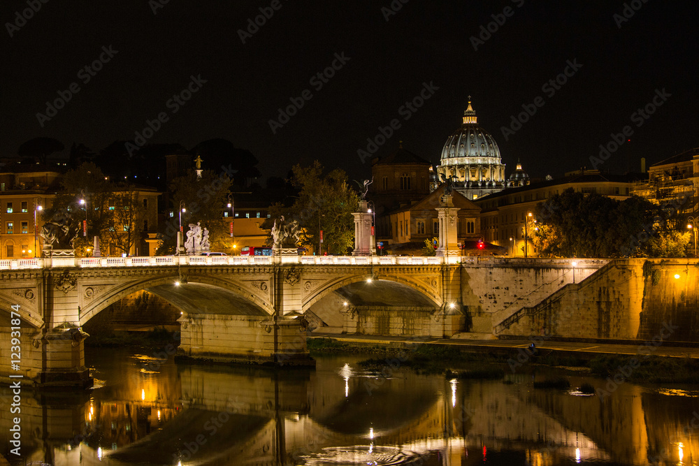 Night view at St. Peter's cathedral and bridge over Tiber river in Rome, Italy