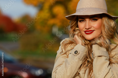 Fashion woman smiling in autumn park. yellow garden background. close-up portrait