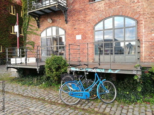 Blaues Hollandrad und Damenrad auf Kopfsteinpflaster vor altem Speichergebäude aus rotbraunem Backstein am Kreativkai an der Hafenpromenade am alten Hafen von Münster in Westfalen im Münsterland photo