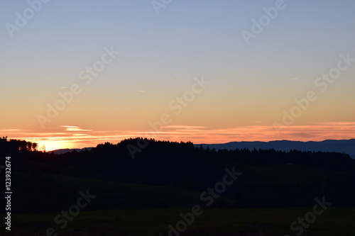 Sonne versinkt in den Wolken hinter den Bergen