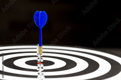 Target dart arrow hitting in the target center of dartboard