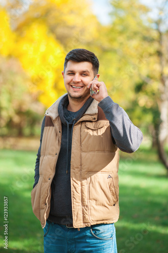 Young man in the park is speaking by phone