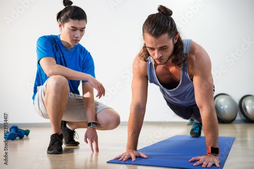 Fitness instructor helping fitness man with push-up photo