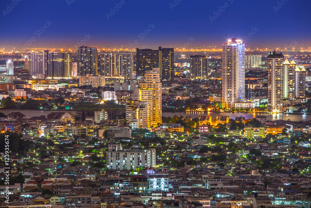 night view of  Bangkok city from small houses to skyscrapers and the Chao Phraya river in between