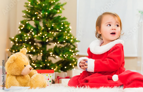 Little girl playing in front of the Christmas tree