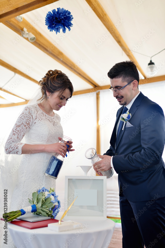 Beauty bride and handsome groom are registering the marriage. Wedding couple is marrying. Beautiful model girl in white dress and in lace veil. Man in suit. Female and male portrait. Cute lady and guy