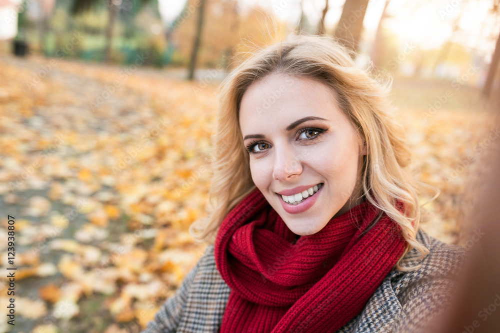 Woman in checked coat taking selfie in autumn park Woman in checked coat taking selfie in autumn park