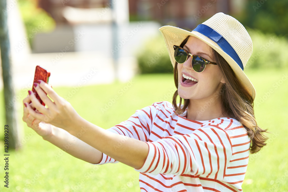 Self portrait. Close-up shot of a happy young woman with her smartphone taking selfie outdoor.